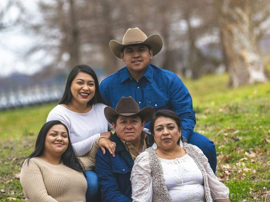 Three generations of a family smiling together outdoors.