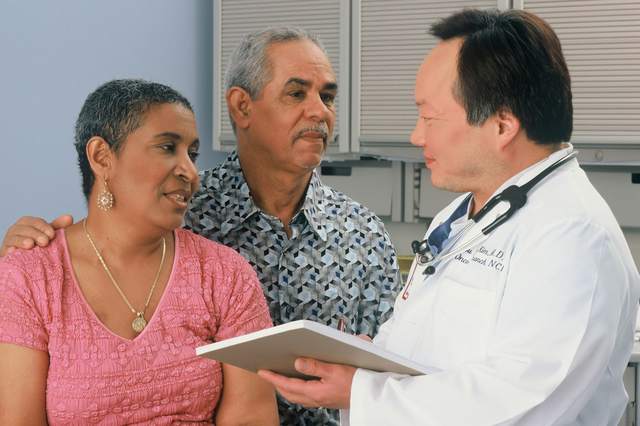 A doctor talks with an older couple.