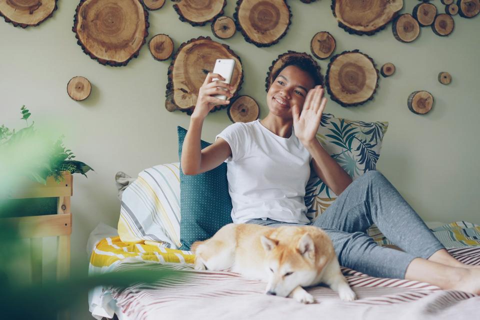 A woman on a video call from her bed.