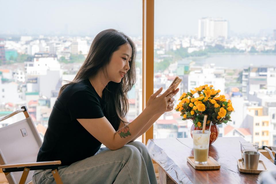 A woman reads a message by a window.
