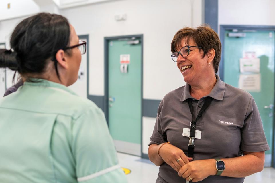 Two nurses talk in a hospital corridor.