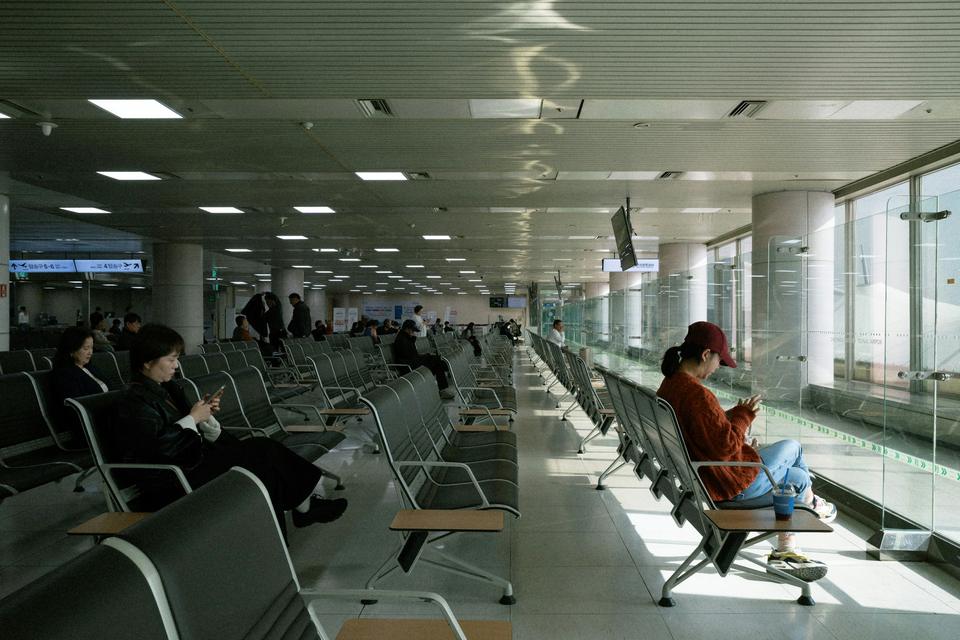 Travelers wait at an airport gate.