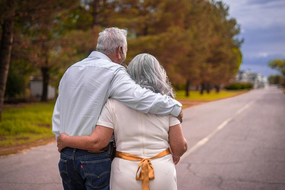 An older couple walks arm in arm.