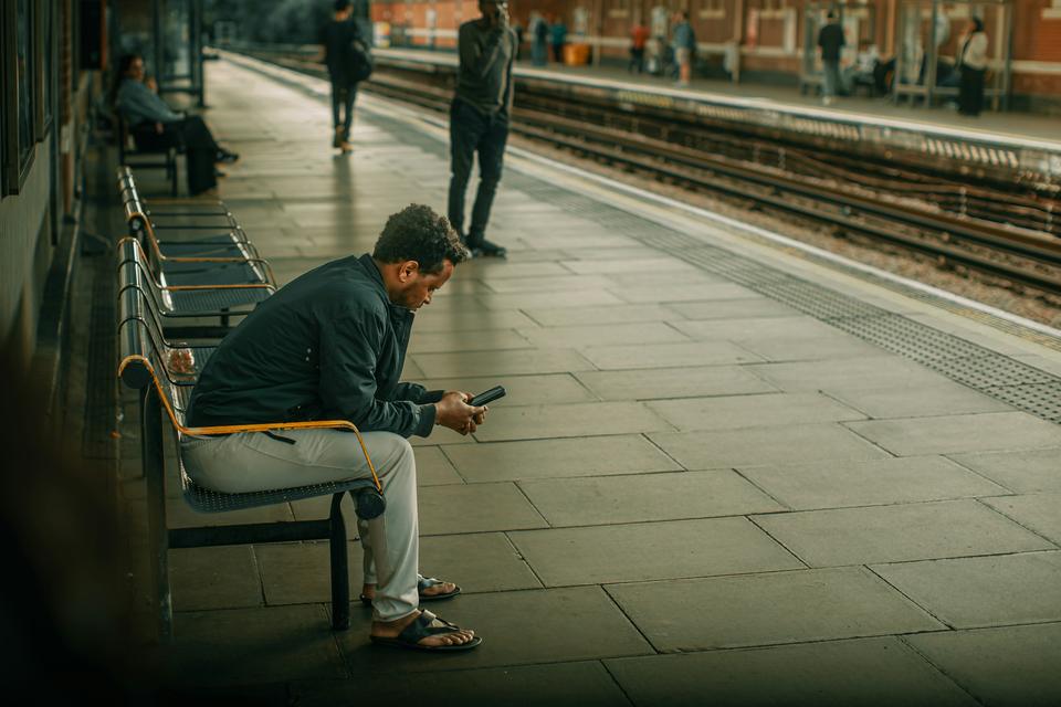A man checks his phone at a station.